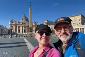 Eine Frau und ein Mann stehen auf dem Petersplatz mit dem Petersdom im Hintergrund.