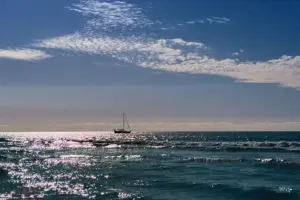 Einsam liegt ein Segelschiff weit vor der Küste vor Anker und wartet auf die Weiterfahrt.