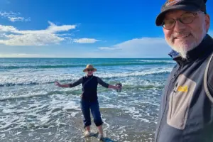 Frau steht barfuss im Wasser und lässt sich von den Wellen die Füsse umspülen.