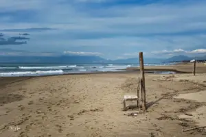Ein einsamer Holzstuhl steht am Strand im Sand.
