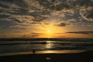 Sonnenuntergang am Strand vor dem offenen Meer mit Wolkenstruktur die schön die Tiefe der Landschaft abbilden.