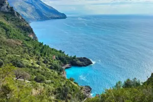 Aussicht aus den Bergen über die Küste am Meer mit türkisfarbigem Wasser.