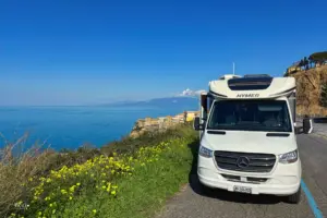 Wohnmobil steht parkiert über der Küste mit freier Sicht über das weite azurblaue Meer