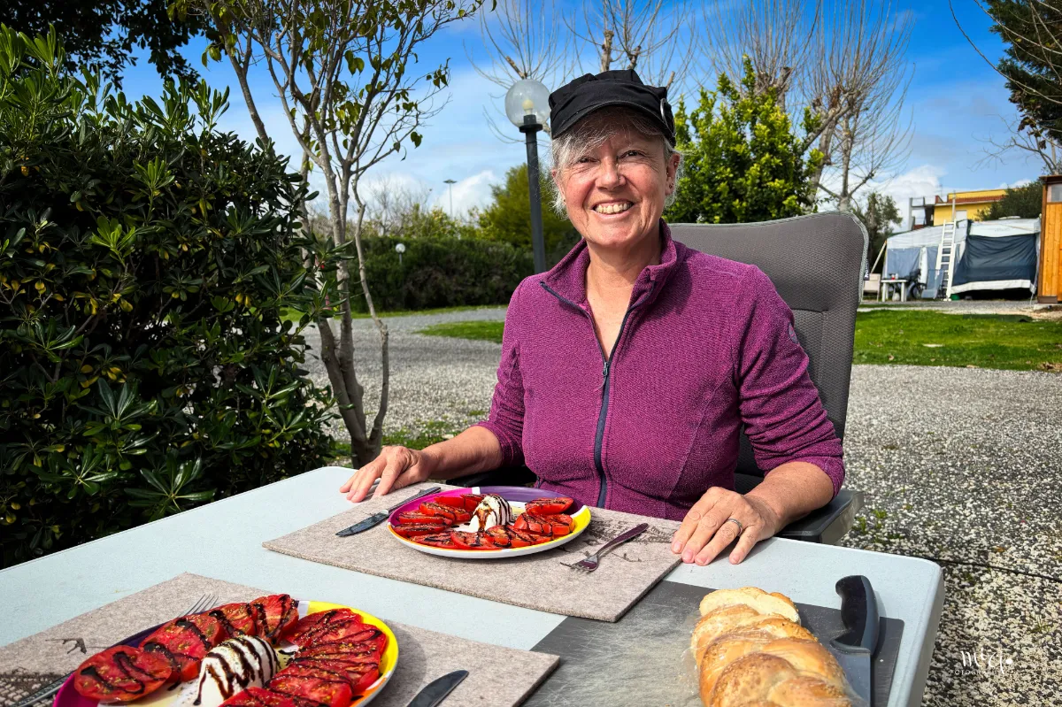 Frau sitzt draussen an der Sonne am Tisch und freut sich auf den Genuss des Salates