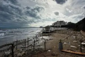Sandstrand der voll von Abfall ist überdeckt von dramatischem Wolkenhimmel