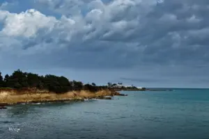 Dramatische Wetterstimmung mit dunklen schweren Wolken und dem Meer in dunklem blau wechselnd mit türkis farbenem Wasser