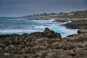 Wellen peitschen an die Felsenküste und das Wasser leuchtet türkisfarben beim brechen der Wellen.