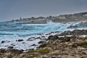 Wellen peitschen an die Felsenküste und das Wasser leuchtet türkisfarben beim brechen der Wellen.