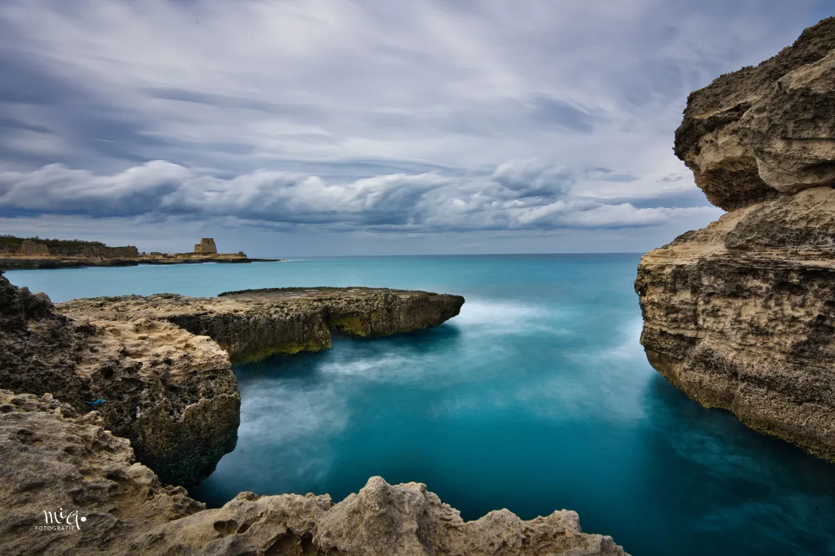 Durch die Langzeitbelichtung wirkt das türkisfarbene Wasser der Küstenlandschaft völlig weich wie es die Felsen umschliesst und die weisse Gischt zieht wie gemalt ihren Bann in das Bild.