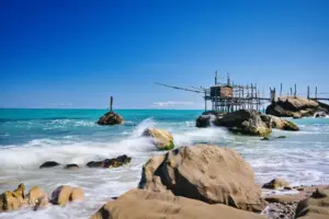 An den Felsen die am Strand vor dem Fischerhaus, Trabocco genannt, liegen, peitschen die Wellen hoch.