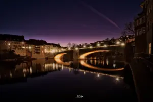 Die alte Brücke von Laufenburg spannt sich über den Rhein und wird in der Abendstimmung schön beleuchtet.