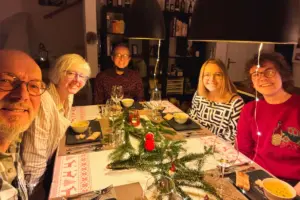 Familie sitzt am Tisch der weihnachtlich dekoriert ist.