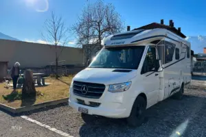 Wohnmobil steht auf dem Stellplatz parkiert bei tollem Wetter.