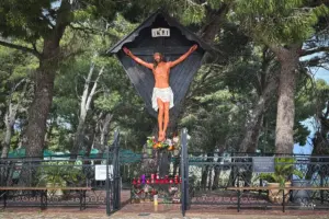 Am Strassenrand steht ein Heiligenkreuz mit dem gekreuzigten Christus und Kerzen als Erinnerung und Opfergabe.