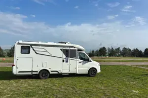 Ein Wohnmobil steht neben dem Pistenrand der Go-Kart-Piste im Gras parkiert.