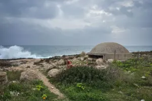 Ein alter Bunker aus dem zweiten Weltkrieg steht verlassen an der Küste zwischen Felsen eingebettet und erinnert an traurige Zeiten.