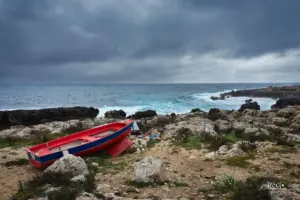 Zwischen den Felsen der Küste liegt ein kleines Fischerboot und wartet auf seinen Einsatz.