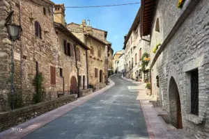 Menschenleere Gasse in der Altstadt von Assisi die links und rechts von historisch alten Häusern flankiert ist.