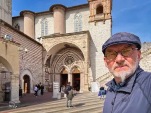 Ein Mann macht ein Selfie von sich mit der Basilika San Francesco im Hintergrund.