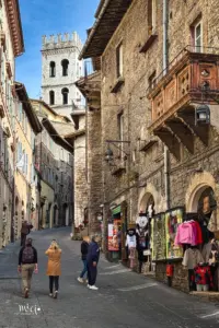 In der Altstadt von Assisi spazieren ein paar Touristen und schauen sich die Auslagen der kleinen Geschäfte an.