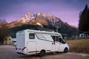 Bei einer schönen Abendstimmung steht das Wohnmobil parkiert vor dem Bergmassiv das im Hintergrund thront und von den letzten Sonnenstrahlen werden die Berggipfel angestrahlt.
