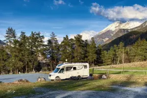 Ein Wohnmobil steht einsam auf dem Stellplatz der mit einem tollen Bergpanorama überzeugt.