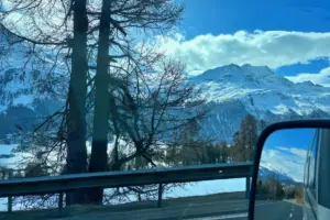 Blick aus dem Wohnmobil auf die Bergwelt und im Rückspiegel ist die dahinterliegende Passstrasse zu sehen.