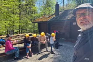 Eine Familie geniesst gemeinsam den Tag im Wald bei einer Waldhütte.