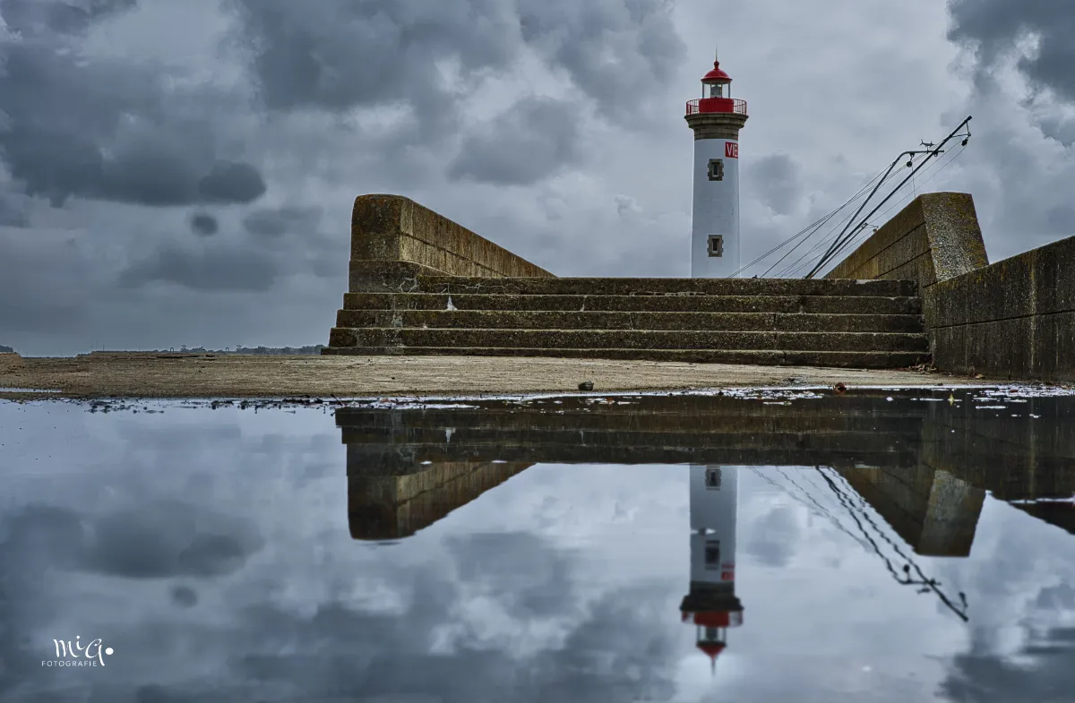 leuchtturm-treppe-spiegelung Bei tristem und regnerischem Wetter spiegelt sich der Leuchtturm von Saint-Nazaire in einer Wasserpfütze.
