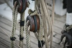 Verschiedene Seile eines alten Segleschiffes hängen an der Reling.